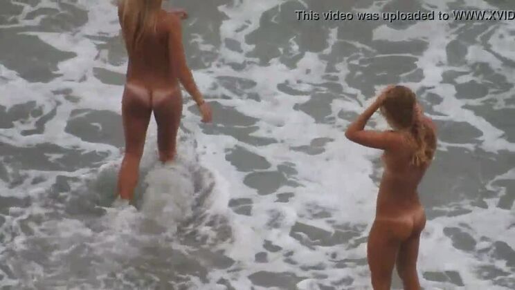 Two blondes bathing naked in the sea.